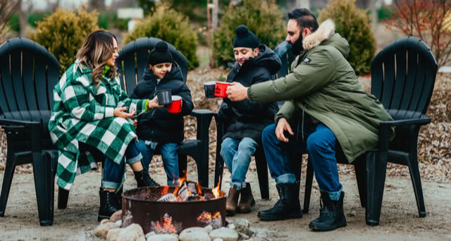 Family sitting together in warm clothes with mugs of hot drinks.