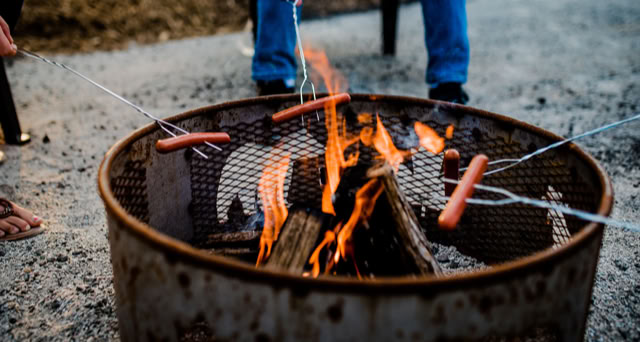 Hot dogs roasting over a fire pit.