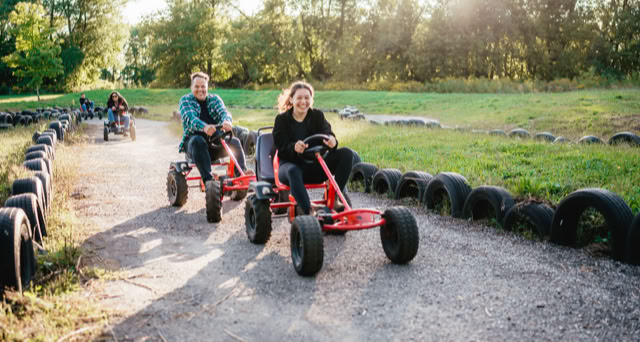 Two people pedaling go-karts on a race course.
