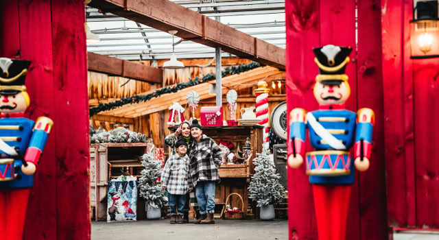 Family visitng a festive market with various christmas decorations.