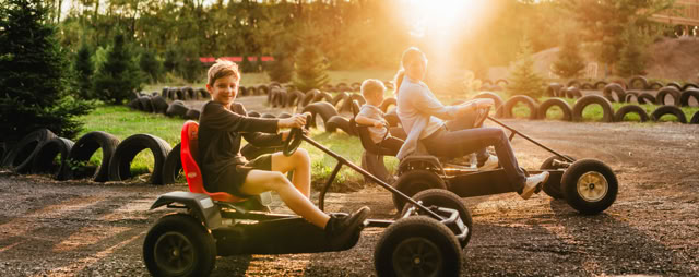 People pedaling go-karts, one with a small child in the back seat.
